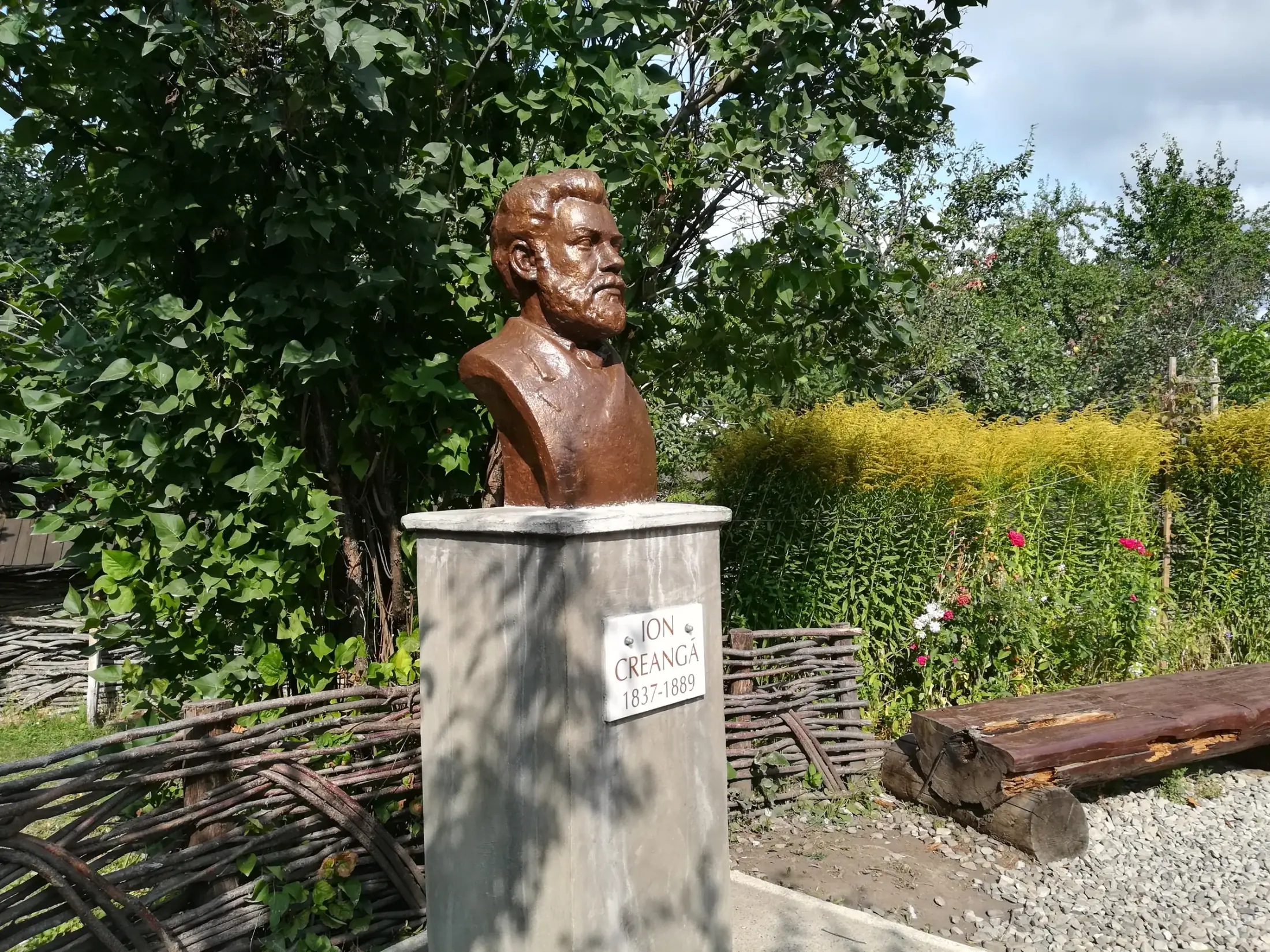 Bustul lui Ion Creangă pe un soclu, în grădina muzeului
