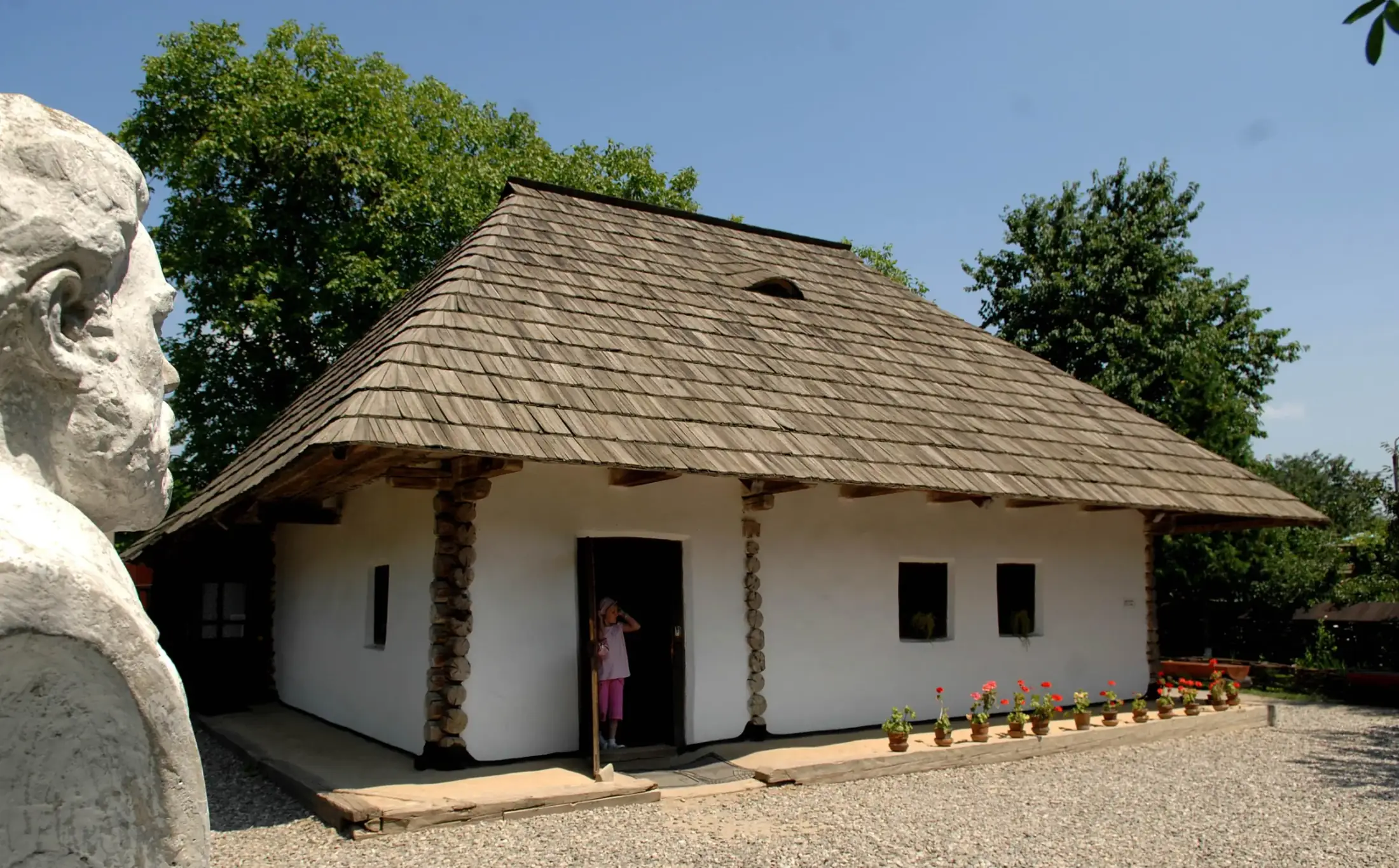 Casa din Humulești, văzută dinspre grădină, cu bustul scriitorului în stânga